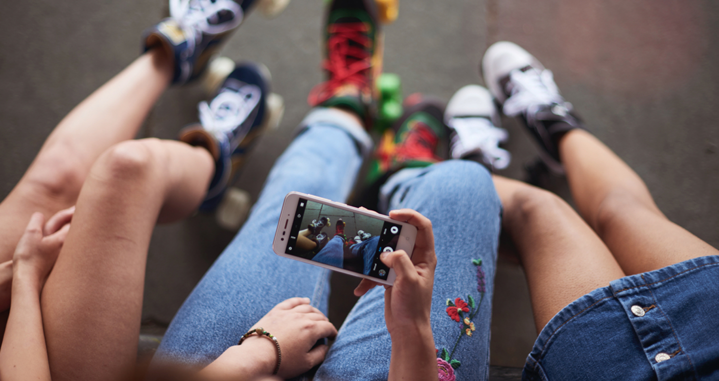 3x Kids looking at mobile phone on lap. Photo by Vodafone